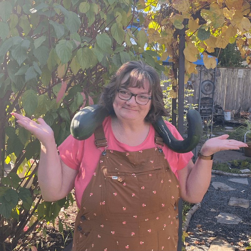 Denise holding a large Tromboncino squash around her neck