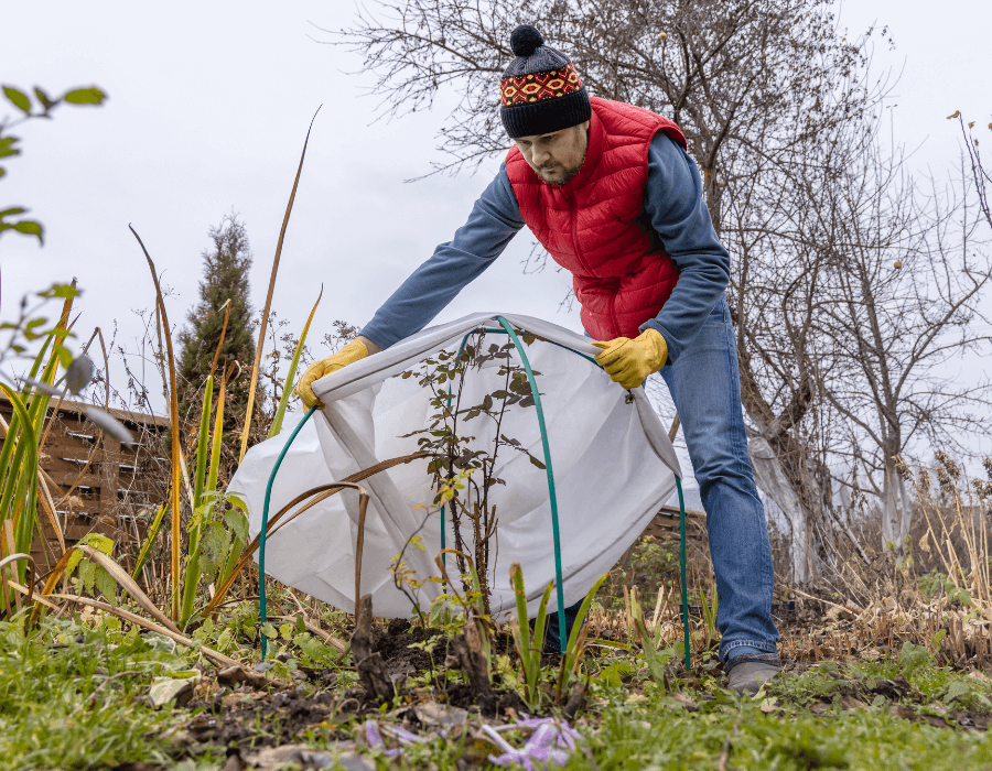 Person applying row cover to their garden in cold weather